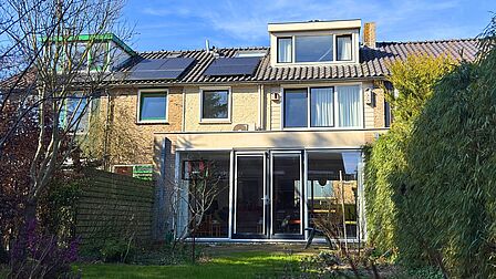Achtergevel met zonnepanelen, warmtepomp buitenunit en uitbouw met groendak