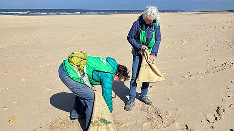 twee vrijwilligers rapen plastic op van het strand