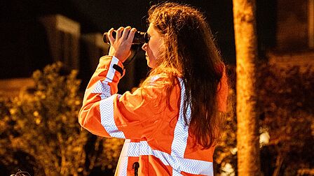 Ecologe van Equipe kijkt door verrekijker naar vleermuis