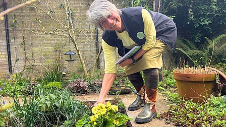 Bregje wijst een bloem aan in haar tuin